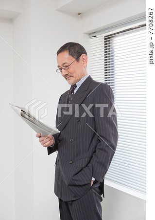 窓辺で新聞を読む上司 7708267