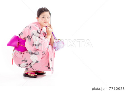 可愛らしく巾着袋を持って座る浴衣を着たキュートな女性の写真素材
