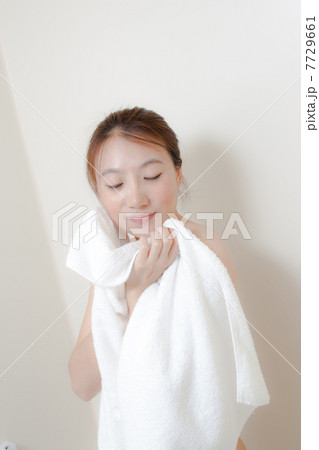 浴室でバスタオルを持っている若い女性 7729661