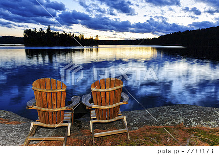 Wooden chairs at sunset on lake shore Wooden chairs at sunset on lake shore 7733173