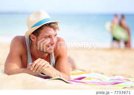Man on beach lying in sand looking to side 7733671