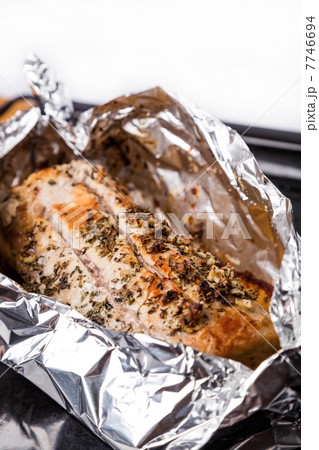 baked meat with seasoning in foil on black tray baked meat with seasoning in foil on black tray 7746694