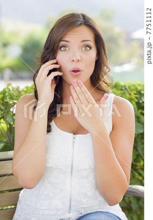 Shocked Young Adult Female Talking on Cell Phone Outdoors 7751112