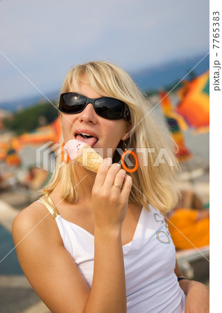 Beautiful young woman eating ice-cream on the beach Beautiful young woman eating ice-cream on the beach 7765383