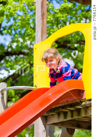 Little Kid on a jungle gym slide 7766154