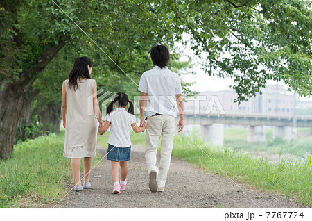 緑の中を歩く3人家族の写真素材
