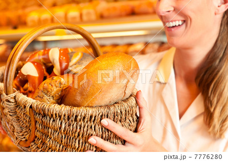 Female baker selling bread by basket in bakery 7776280