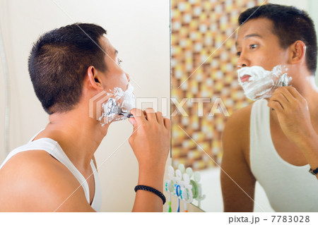 Asian man shaving in front of mirror 7783028