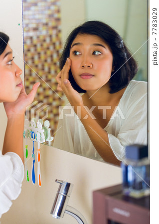 Asian woman discovering a pimple in face Asian woman discovering a pimple in face 7783029