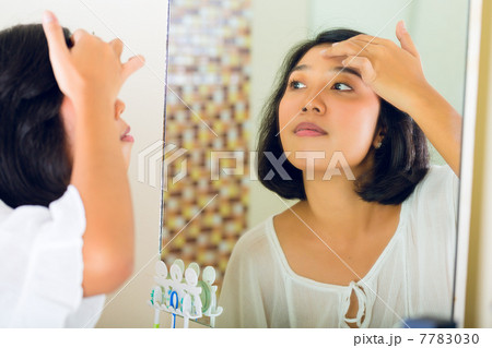 Asian woman discovering a pimple in face 7783030