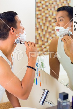 Asian man shaving in front of mirror 7783032