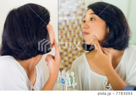Asian woman discovering a pimple in face Asian woman discovering a pimple in face 7783093