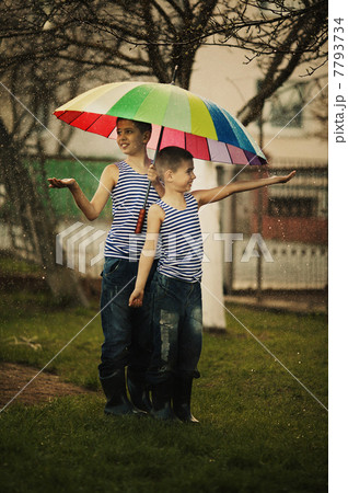two boys with rainbow umbrella in park two boys with rainbow umbrella in park 7793734