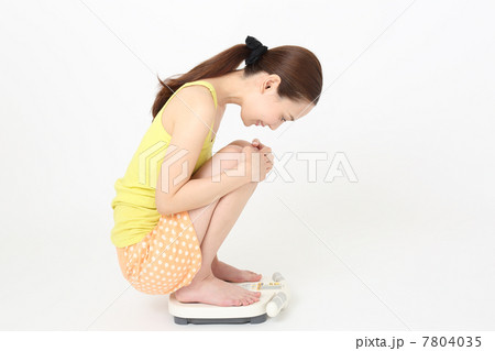 ヘルスメーターに乗っている若い女性 7804035