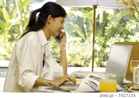 Young woman making phone calls while checking computer Young woman making phone calls while checking computer 7827138