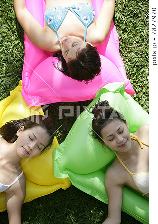 Three young women lying on pool raft 7827970