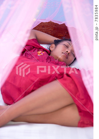 woman sleeping under a mosquito net 7835984