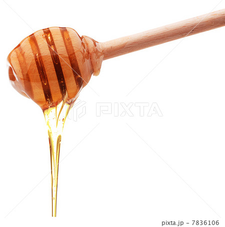 Honey dripping from a wooden honey dipper isolated on white back 7836106