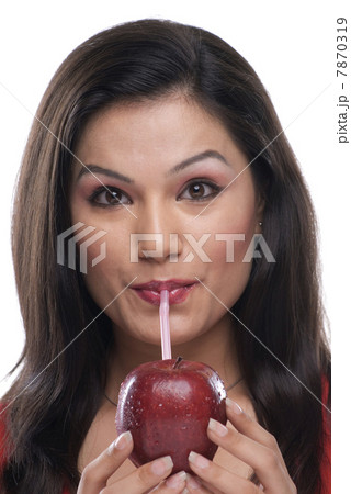 Woman sipping juice from an apple Woman sipping juice from an apple 7870319