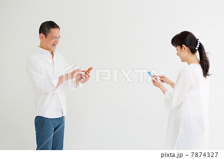 向かい合わせでスマートフォンを使うシニア夫婦 7874327