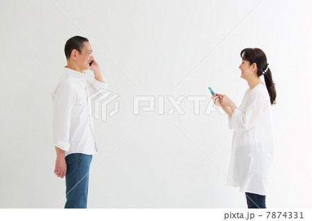 向かい合わせでスマートフォンを使うシニア夫婦 7874331
