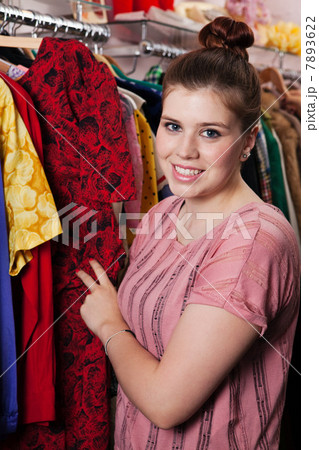 Young woman looking at dress in clothes shop, portrait Young woman looking at dress in clothes shop, portrait 7893622