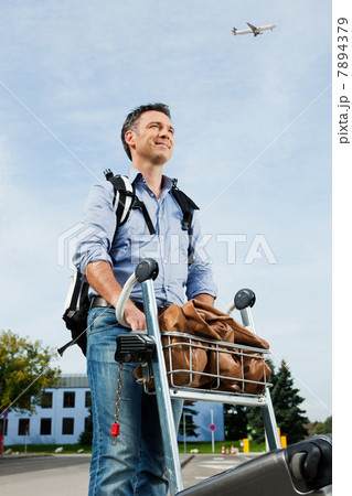 Mid adult man pushing luggage trolley at airport 7894379