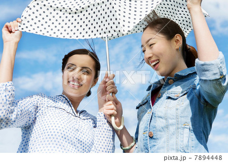 Two young women outdoors with parasol Two young women outdoors with parasol 7894448