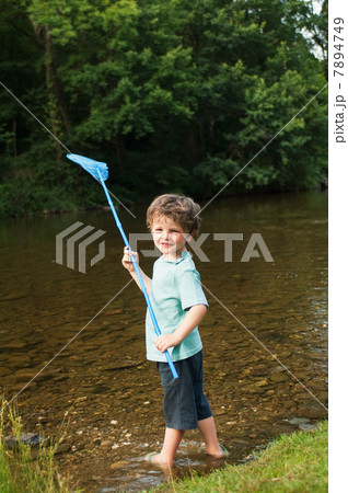Boy holding fishing net by river Boy holding fishing net by river 7894749