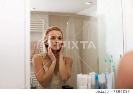 Young woman looking in bathroom mirror Young woman looking in bathroom mirror 7894857