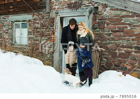 Family outside rustic house in snow 7895016