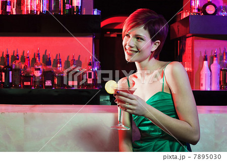 Happy young woman sitting at cocktail bar 7895030