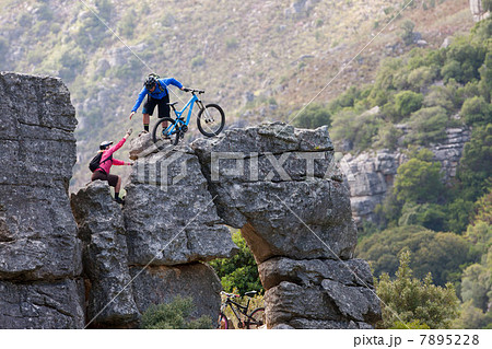 Mountain biking couple climbing rock formation Mountain biking couple climbing rock formation 7895228