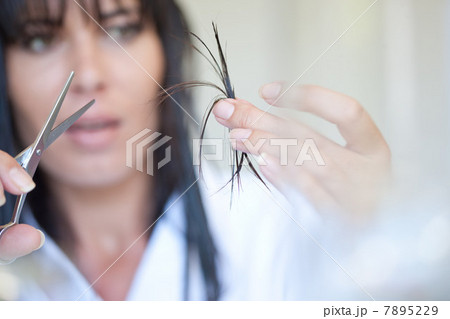 Mid adult woman holding scissors and hair 7895229