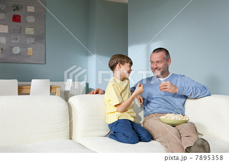 Father and son watching television eating popcorn 7895358