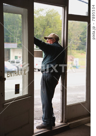 Senior man in doorway of store, looking out Senior man in doorway of store, looking out 7895534