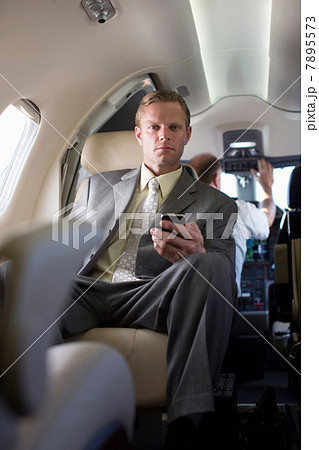Businessman using cell phone on airplane Businessman using cell phone on airplane 7895573