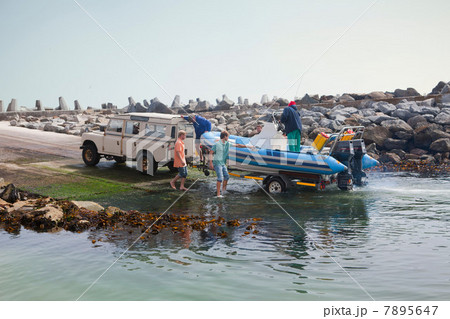 Small group of men landing dinghy onto trailer in harbor Small group of men landing dinghy onto trailer in harbor 7895647