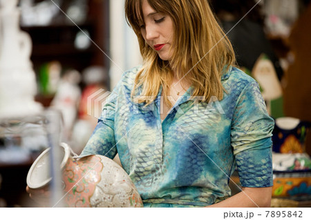 Woman inspecting vase in antiques shop 7895842