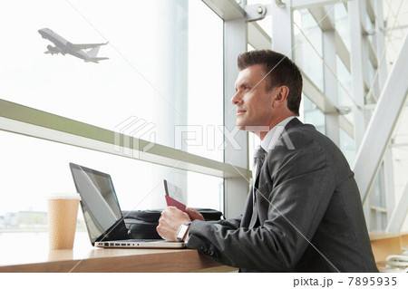 Businessman using laptop in airport Businessman using laptop in airport 7895935