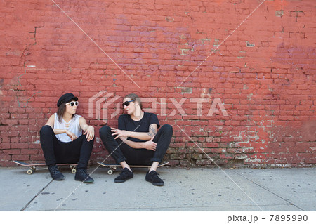 Skaters sitting on boards by wall 7895990