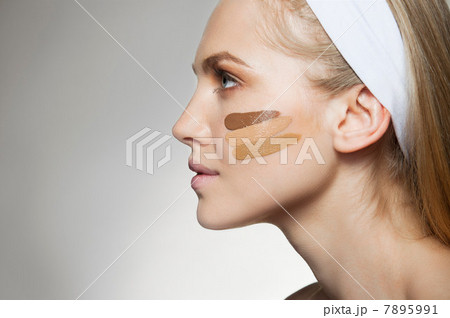 Woman with stripes of foundation on cheek 7895991