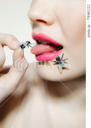 Young woman with plastic fly on tongue 7896122