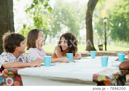 Children sitting at picnic table at birthday party 7896200