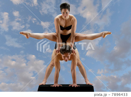 Mid adult dancers balancing on top of each other against blue sky 7896433