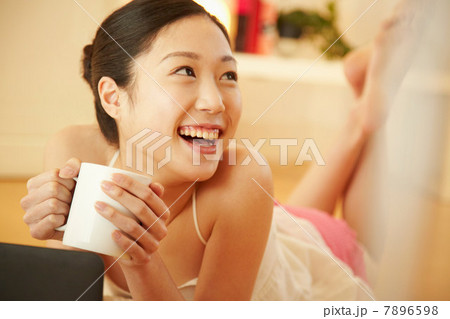 Woman lying on front with mug, laughing 7896598