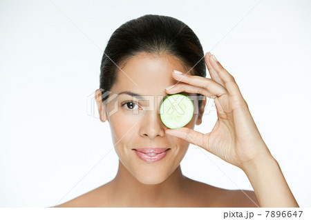 Woman holding cucumber over eye Woman holding cucumber over eye 7896647
