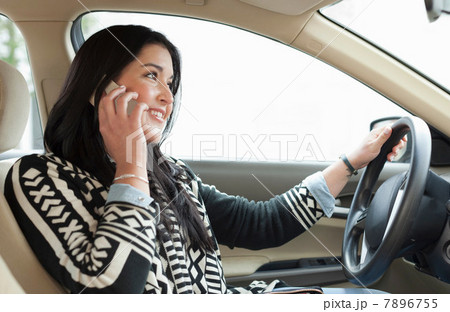 Young woman on cell phone driving car 7896755