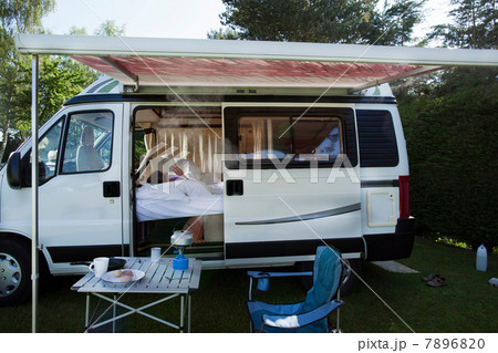 Mature woman drinking reading book in camper van 7896820