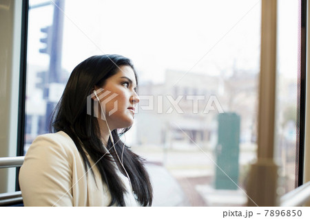 Young woman traveling on light train wearing earphones 7896850